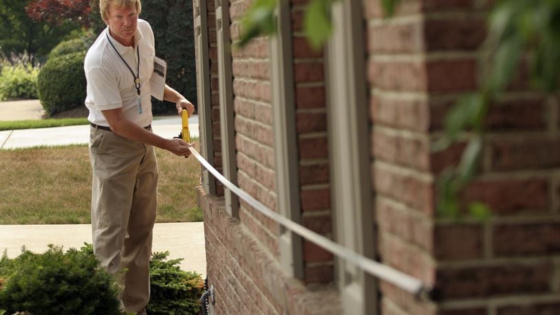 Tom Schoemaker, a Montgomery County Data Collector, takes a measurement on an exterior wall to verify the accuracy of the dimensions on the property record card in the Savina Hill Estates neighborhood. FILE
