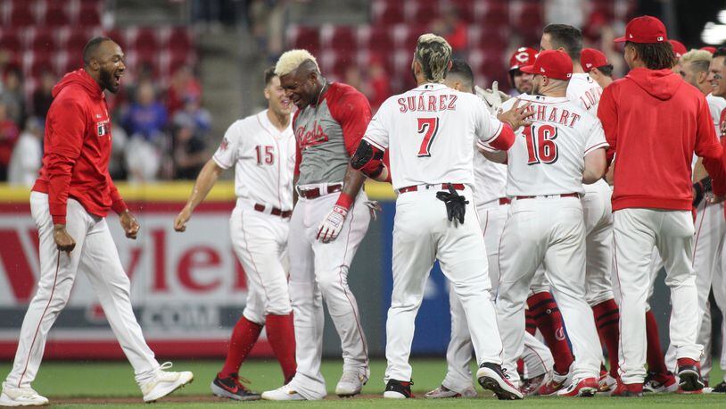 The Reds celebrate after a game-winning hit by Yasiel Puig against the Cubs in the 10th inning on Wednesday, May 15, 2019, at Great American Ball Park in Cincinnati. David Jablonski/Staff