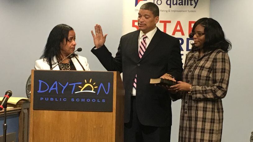 William Harris (center) is sworn in by Treasurer Hiwot Abraha (left) to serve on the Dayton school board, as Harris’ wife, Lynn Harris, looks on Tuesday, Nov. 21. JEREMY P. KELLEY / STAFF