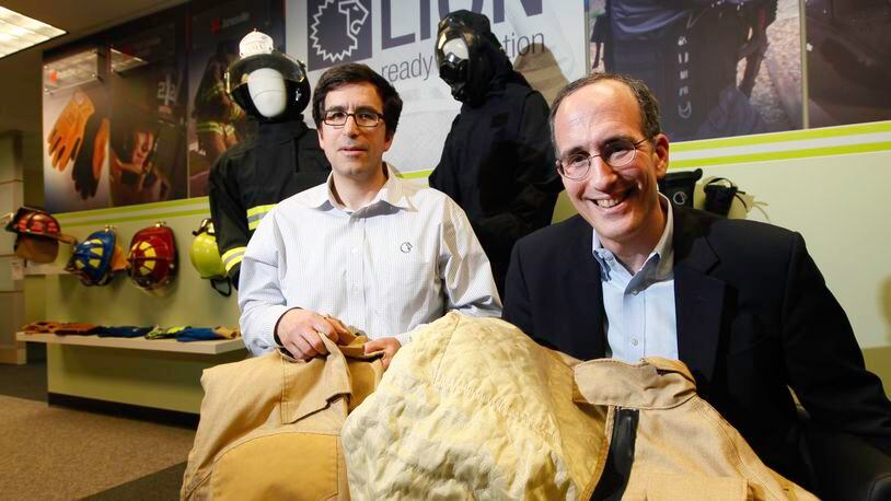 LION CEO Steve Schwartz, right, and his brother Andy Schwartz, corporate counsel, are the grandsons of founder William Lapedes. The two are seen with the company’s Janesville turnout for firefighters that incorporates a new Kevlar filament and Nomex blend.CHRIS STEWART / STAFF