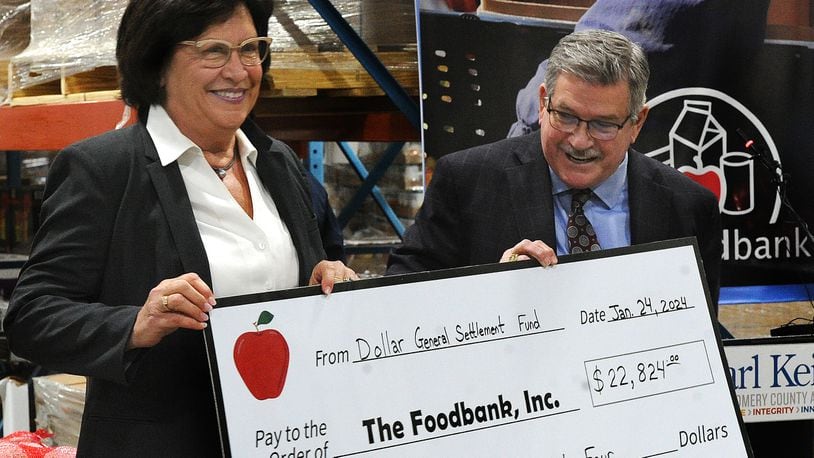 Foodbank Inc. CEO Michelle Riley and Montgomery County Auditor Karl Keith hold up a check Wednesday, Jan. 24, 2024 that represents the Dollar General settlement money passed along to the foodbank network on Dec. 24, 2023. MARSHALL GORBY\STAFF
