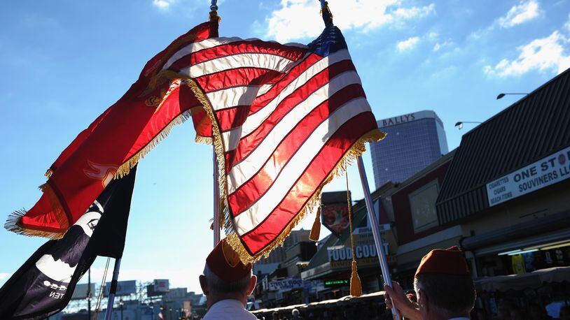 A photo of veterans holding American and miltary flags in a parade. A Florida business was cited by the City of Jacksonville for flying military flags atop its building because it violates a city ordinance.