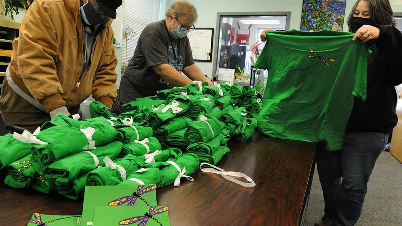 Goodwill Easterseals Miami Valley Miracle Clubhouse is celebrating its 10 year anniversary Tuesday. From left, Darrell Crenshaw, Steve Tretchler and Jennifer Mullins folds shirts created for the celebration. MARSHALL GORBY\STAFF 