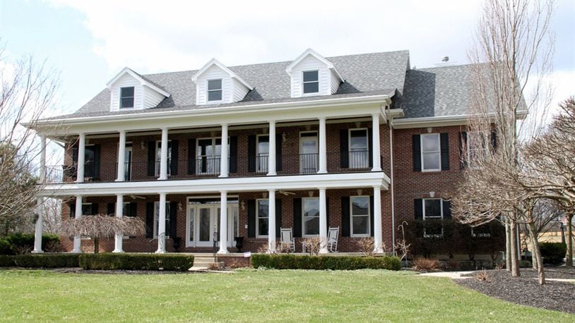 Mature trees and professional landscaping flank the facade of this 2-story brick home in Beavercreek Twp. Southern Colonial styling with white columns edging the upper and lower porches incorporates dormers on the third-level rooftop. CONTRIBUTED PHOTOS BY KATHY TYLER