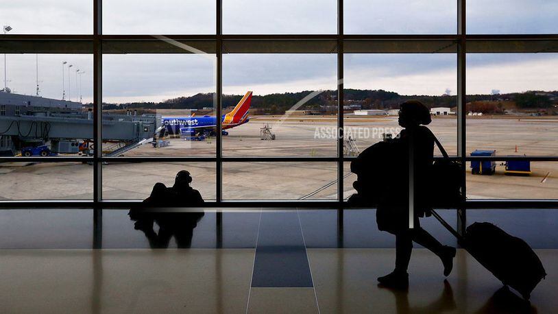 FILE- IN this Dec. 19, 2016, file photo, travelers walk through a the airport to board an airplane during holiday travel at the Birmingham-Shuttlesworth International Airport in Birmingham, Ala. Major airlines including American Airlines, JetBlue, Southwest Airlines and United Airlines integrate buy-now-pay-later concepts into their online booking. (AP Photo/Brynn Anderson, File)