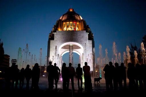 Pedestrians stand in front of the Arch of the Revolution monument in Mexico City.