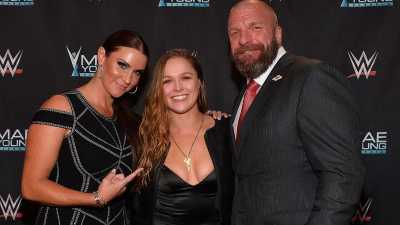 Ronda Rousey, flanked by the WWE's Stephanie McMahon and Paul "Triple H" Levesque, officially joined the WWE Sunday night with a surprise appearance at the inaugural women's Royal Rumble.
