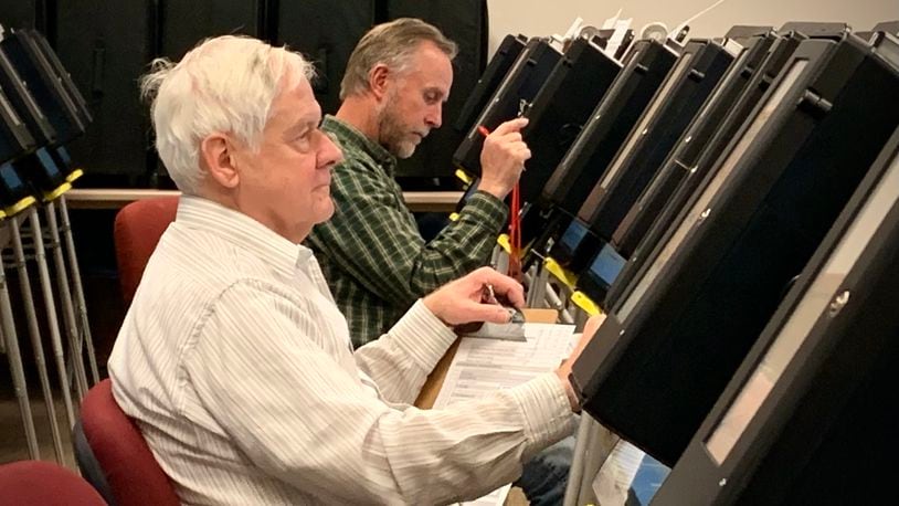 Two elderly seasonal poll workers with the Greene County Board of Elections test rows of voting machines in preparation for early voting.