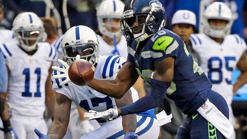 Seattle Seahawks cornerback Justin Coleman, right, intercepts a pass intended for Indianapolis Colts wide receiver Kamar Aiken, center, in the first half of an NFL football game, Sunday, Oct. 1, 2017, in Seattle. Coleman returned the pick for a touchdown. (AP Photo/Elaine Thompson)