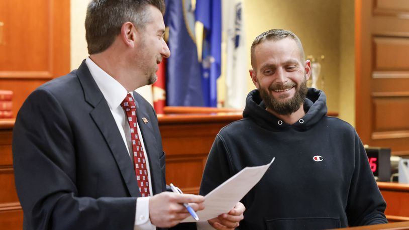 Judge Michael A. Oster Jr., left, signs the final papers for Army veteran David Berryman during Veterans Treatment Court graduation Tuesday, Nov. 15, 2022 in Butler County Common Pleas Court in Hamilton. This class had three graduates for a combined total of 25 graduates since Veterans Treatment Court started in 2017. NICK GRAHAM/STAFF