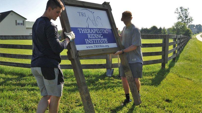Air Force Academy Cadets Zack LaRocque, left, and Evan Place position a new sign for the Therapeutic Riding Institute to mark the locations needed to dig holes. After quality time with shovels, the duo were able to permanently place the institute s sign at the property s entrance. LaRocque, Place and 18 fellow cadets travelled to Spring Valley July 6 to volunteer with the institute, readying its new location to begin operations. (U.S. Air Force photo/John Van Winkle)