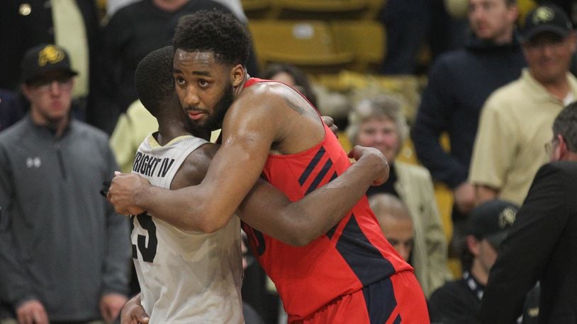 Dayton's Josh Cunningham hugs Colorado's McKinley Wright after a loss in the first round of the NIT on Tuesday, March 19, 2019, at the CU Events Center in Boulder, Colo.