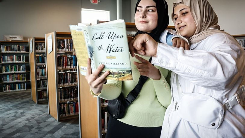 Amina Muradova, left and Aydina Fakhratov, both from Dayton, check out a book during the grand opening of the Dayton Metro Library Huber Heights Branch Friday June 2, 2023. JIM NOELKER/STAFF