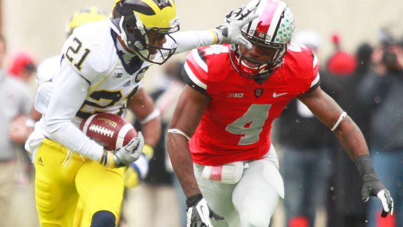 Roy Roundtree (left) of Michigan is pursued by C.J. Barnett of Ohio State during a 2012 game at Ohio Stadium in Columbus. Roundtree played at Trotwood-Madison High School and Barnett at Northmont. FILE PHOTO