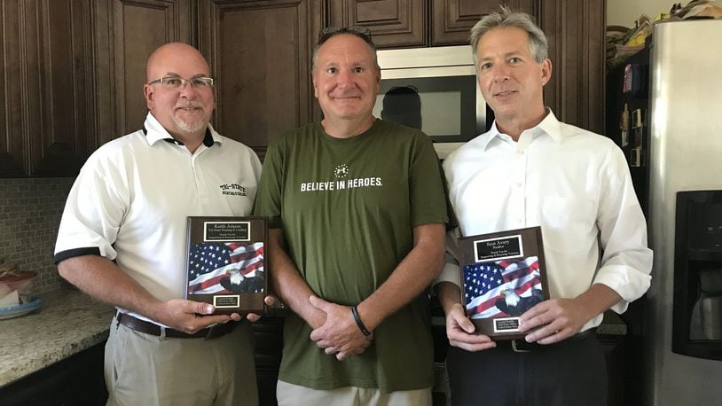 Tri-State Heating and Cooling President Keith Adams (left) and Huff Realty Senior Sales Vice President Scot Avery (right) hold the plaques retired Navy Chief Petty Officer Leonard Koebbe (center) gave them for helping him move into his new home. STAFF/EMMA STIEFEL