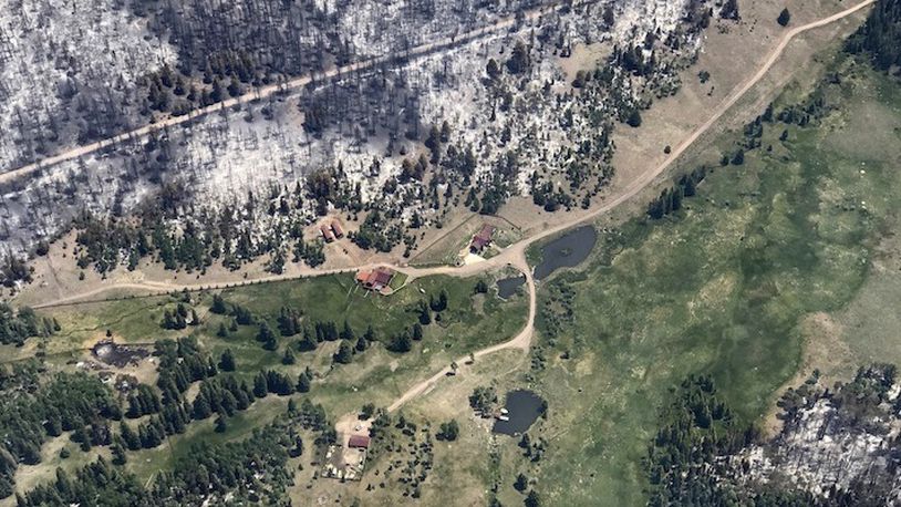 This Monday, June 27, 2017, taken by Justin Harding, shows spared cabins near burnout areas around Panguitch Lake, during a wildfire tour by Utah Lt. Gov. Spencer Cox, in southern Utah. The nation's largest wildfire has forced more than 1,500 people from their homes and cabins in a southern Utah mountain area home to a ski town and popular fishing lake. (Justin Harding/ State of Utah, Office of the Governor, via AP)