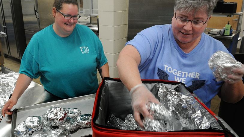 Fairborn City School staff, Left, Kristine Van Meter, and Jackie Hazelett, place warm chicken sandwiches into thermal bags for free lunches at the Fairborn Primary School and to be delivered to the Fairborn library for free lunches, Thursday 23, 2022. MARSHALL GORBY\STAFF