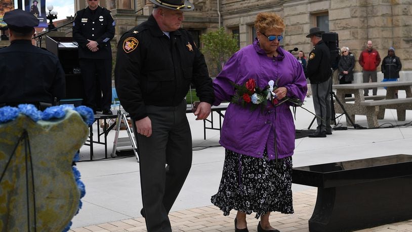 Tammie Elliott-Gehle, whose husband Robert L. Elliott was killed in the line of duty Feb. 25, 1987, is escorted to the memorial by Chief Deputy Steve Lord of the Miami County Sheriff's Department.