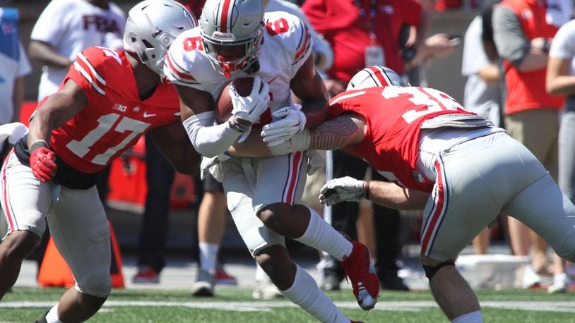 Ohio State’s Torrance Gibson, center, is tackled by Jerome Baker, left, and Zach Turnure during the spring game April 16 at Ohio Stadium in Columbus. David Jablonski/Staff