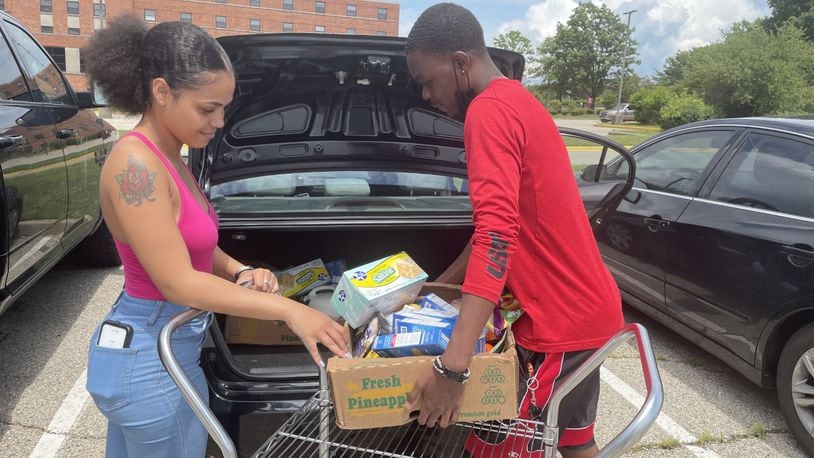 The Community Marketplace mobile food pantry student volunteer Emmitt Higgins, right, helps a student, Teesh J., at a recent food distribution event at Central State University's campus. ,The pantry happens the second Tuesday of every month to help students and nearby community members. ADRIENNE OGLESBY/STAFF