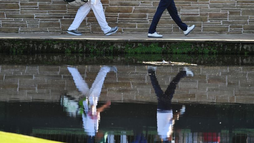 Phil Mickelson and his caddie, Jim Mackay, walk across the bridge on the 15th hole on Saturday. BRANT SANDERLIN / SPECIAL