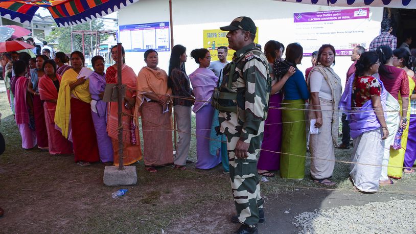 A Border Security Force soldier stands guard as women queue up to vote during a re-polling in Imphal West District, Manipur, India, Monday, April 22, 2024. Voters at some polling places in this northeastern state went back to the polls amid tight security on Monday after violence disrupted the vote last week. (AP Photo/Bullu Raj)