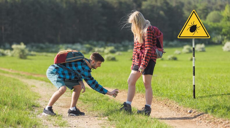 Man and woman spraying with tick repellent while hiking. iSTOCK/COX
