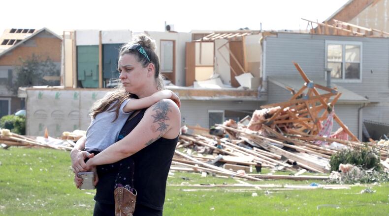 Meghan Porter and daughter Gemma,6, of Beavercreek stand in front of a damaged apartment complex. Porter said her childhood home in Beavercreek was destroyed. BILL LACKEY/STAFF PHOTOGRAPHER