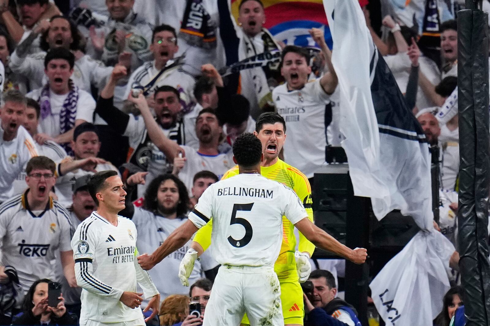 Real Madrid's goalkeeper Thibaut Courtois, right, reacts after saving a penalty shot by Arsenal's Bukayo Saka during the Champions League quarterfinals second leg soccer match between Real Madrid and Arsenal at the Santiago Bernabeu stadium in Madrid, Wednesday, April 16, 2025. (AP Photo/Manu Fernandez)