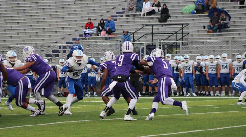 Middletown quarterback Zach Maloney (9) hands off to Diondre Cooper (5) as Springboro’s Cameron Piper (65) comes forward during Friday night’s game at Barnitz Stadium in Middletown. CONTRIBUTED PHOTO BY MARITZA MCKINNEY