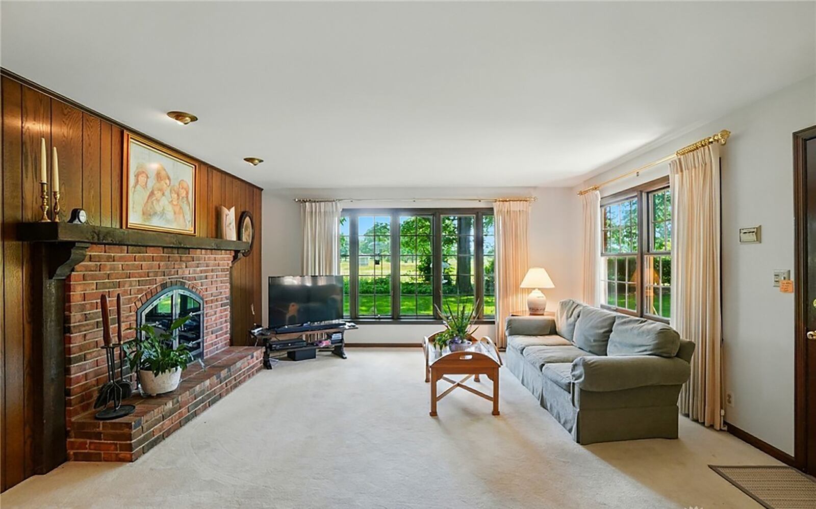 The family room is at the rear of the home and has a woodburning brick fireplace, carpeting and recessed lighting.