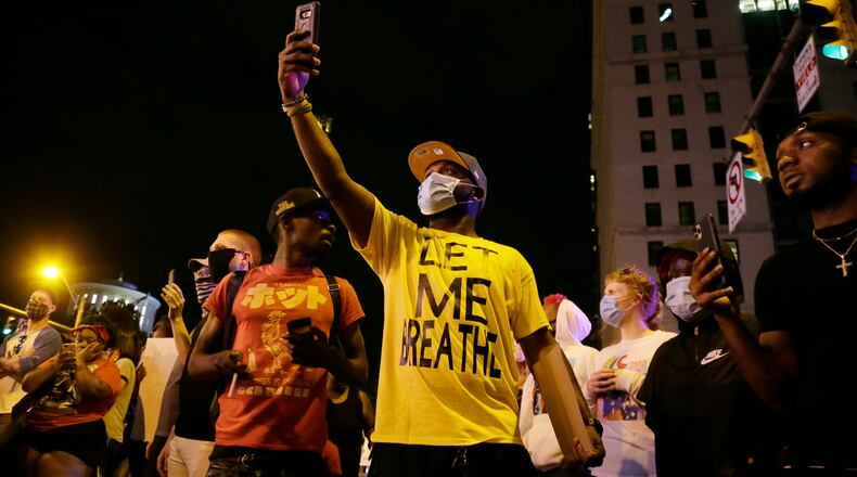 Protesters stand in downtown Columbus, Ohio, Thursday, May 28, 2020, during a demonstration over the death of George Floyd in police custody Monday in Minneapolis. Columbus police used pepper spray to disperse protesters after some threw plastic bottles of water, smoke bombs and other items at police. Windows at the Statehouse and in bus stations along High Street were shattered, trash cans were tossed and decorative planters wrecked. (Barbara J. Perenic/The Columbus Dispatch via AP)