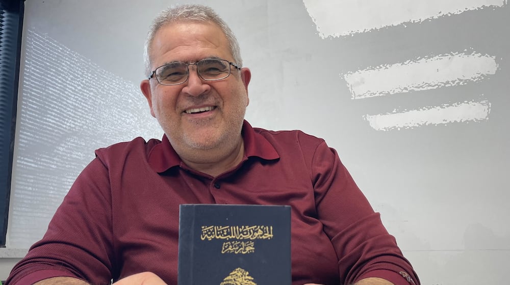 Youssef Elzein holds up his passport, a token of his youth in Lebanon.