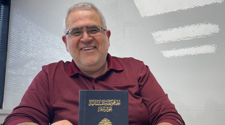 Youssef Elzein holds up his passport, a token of his youth in Lebanon.