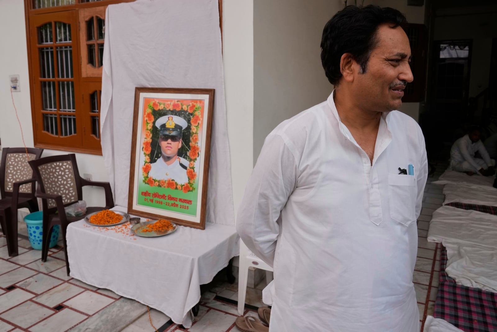 Sunil Swami stands next to a framed portrait of his son-in-law and Indian naval officer Vinay Narwal, who was killed by militants at Pahalgam in Indian controlled Kashmir, at Narwal's home in Karnal, India, Tuesday, April 29, 2025.(AP Photo/Manish Swarup)