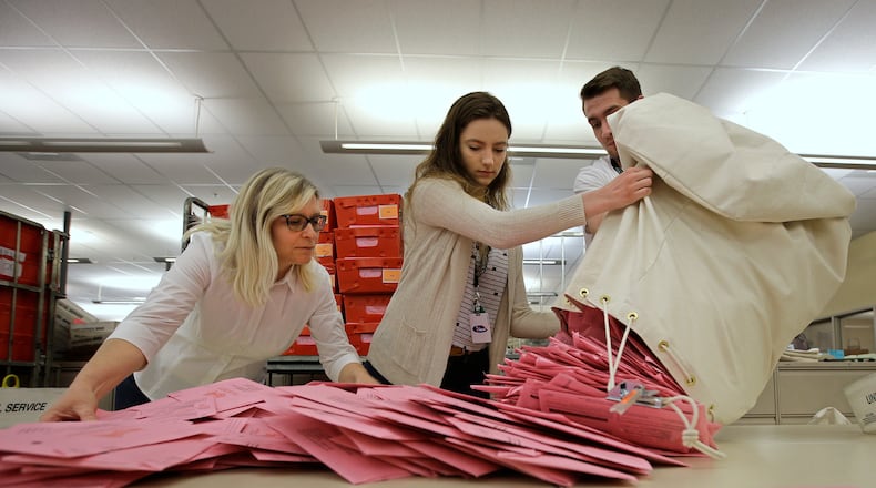 FILE - Election workers Heidi McGettigan, left, Margaret Wohlford, center, and David Jensen, unload a bag of ballots brought in a from a polling precinct to the Sacramento County Registrar of Voters office in Sacramento, Calif., June 5, 2018. (AP Photo/Rich Pedroncelli, File)