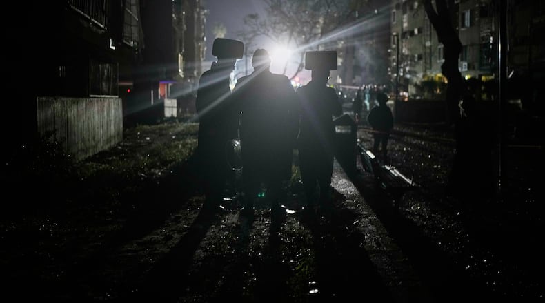 Ultra-Orthodox Jewish men watch as Israeli security forces and rescue teams operate at the site hit by an Iranian missile in Arad, southern Israel, Sunday, March 22, 2026. (AP Photo/Ohad Zwigenberg)