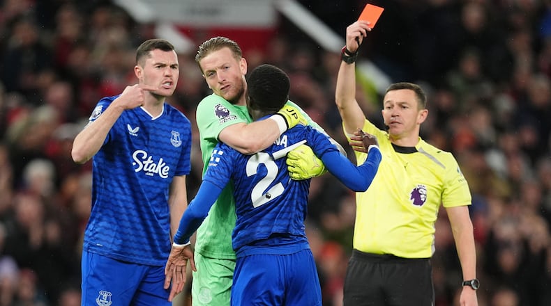 Everton's Idrissa Gueye, second right, is held back by teammate Jordan Pickford as he argues with Michael Keane, left, after getting a red card from referee Tony Harrington during the English Premier League soccer match between Manchester United and Everton in Manchester, England, Monday, Nov. 24, 2025. (Martin Rickett/PA via AP)