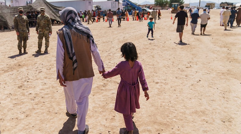 FILE - A man walks with a child through Fort Bliss' Doña Ana Village where Afghan refugees are being housed, in New Mexico, Friday, Sept. 10, 2021. (AP Photo/David Goldman, File)