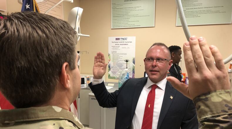 Dr. Mark Gebhart, 53, is commissioned as a lieutenant colonel into the U.S. Army reserves Wednesday morning during a ceremony in an Emergency Department bay at Atrium Medical Center. His commissioning officer is U.S. Air Force Capt. Dr. Eric Mozeleski, his close friend who works for the emergency department at WPAFB. RICK McCRABB/STAFF
