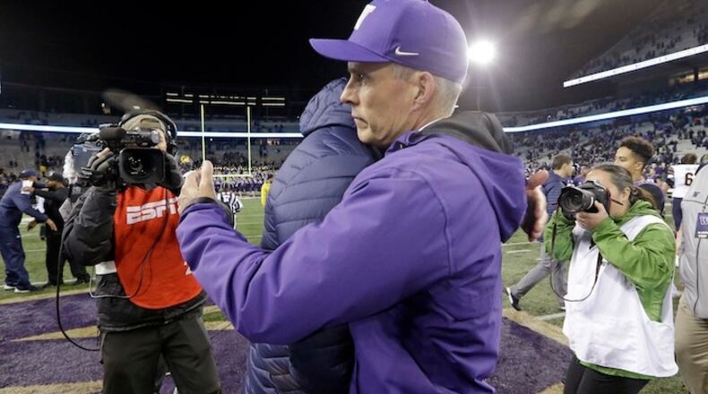 In this photo taken Saturday, Oct. 7, 2017, an ESPN video operator, left, looks on as Washington head coach Chris Petersen, right, embraces California head coach Justin Wilcox after their NCAA college football game ended shortly before 11 p.m., in Seattle. Petersen has moved on from the debate over Pac-12 After Dark, those late-night televised conference games that end in the wee hours on the East Coast. The issue was amplified in a not-so-good way over the weekend when Kirk Herbstreit said on ESPN's College Game Day that Petersen "should be thanking ESPN for actually having a relationship." (AP Photo/Elaine Thompson)