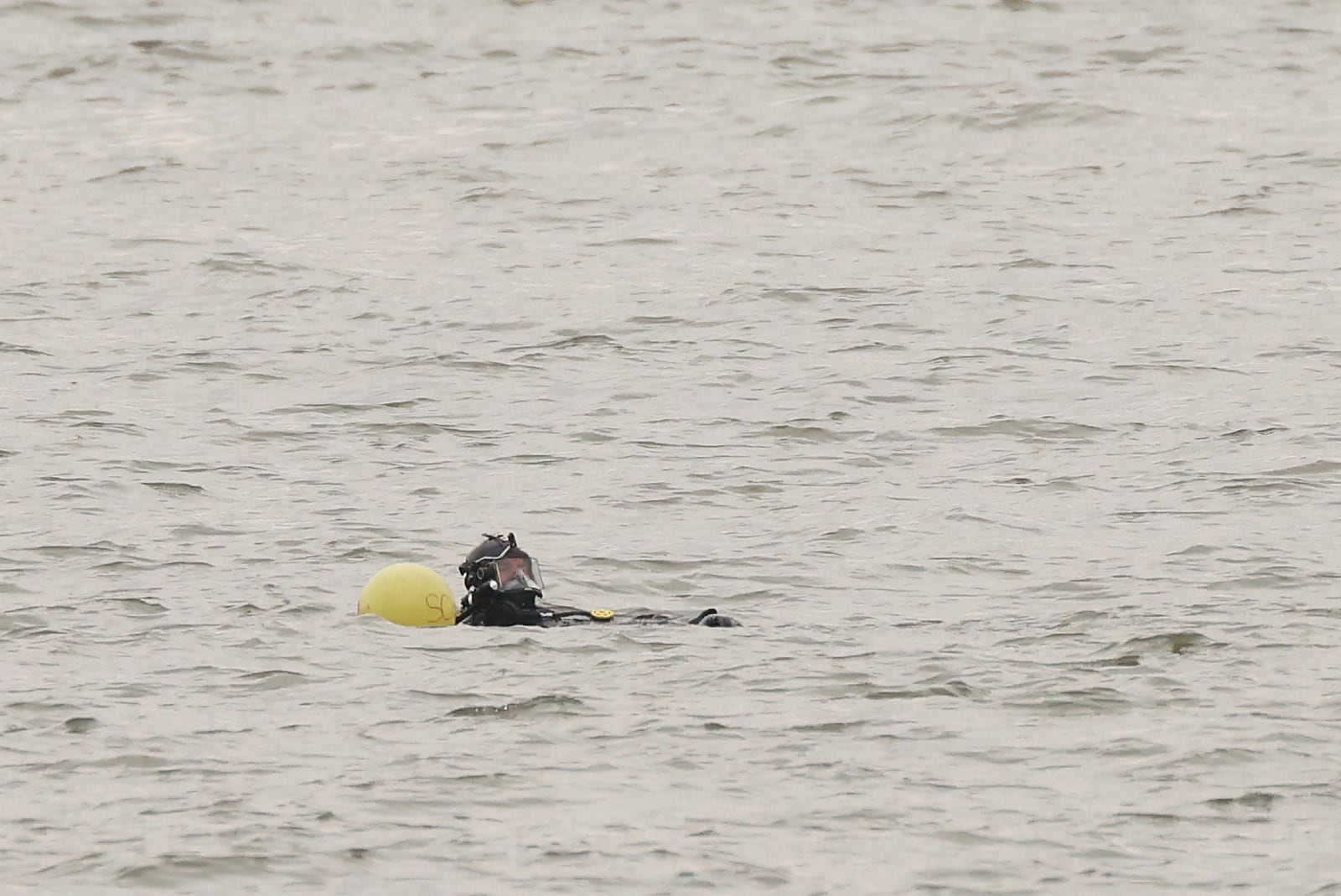 A New York Police Department scuba team diver prepares to search underwater, Friday, April 11, 2025, at the site where a sightseeing helicopter crashed a day earlier into the Hudson River in Jersey City, N.J. (AP Photo/Yuki Iwamura)