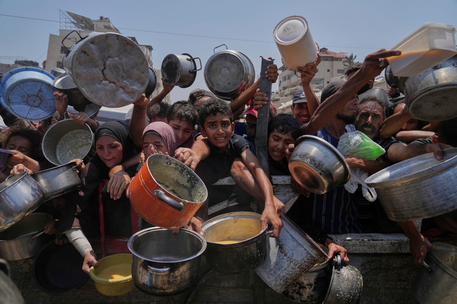 Palestinians struggle to get donated food at a community kitchen, in Gaza City, northern Gaza Strip, Saturday, July 26, 2025. (AP Photo/Abdel Kareem Hana)