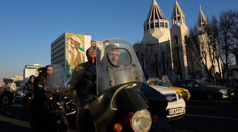 Commuters drive past Saint Sarkis church and a mural of the late Iranian revolutionary founder Ayatollah Khomeini in downtown Tehran, Iran, Wednesday, Feb. 25, 2026. (AP Photo/Vahid Salemi)