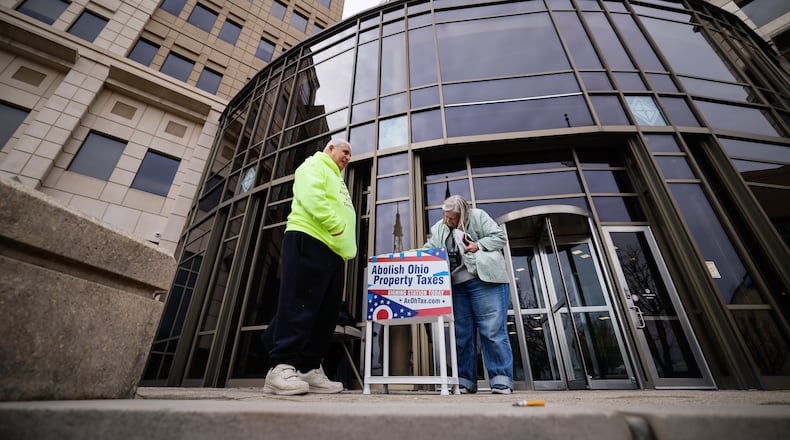 Ed Maloof, left, with AxOhioTax, gets signature from Donna Trueman Bryant as she goes to pay taxes Thursday, Feb. 26, 2026 at Butler County Government Services Center building on High Street in Hamilton. AxOhioTax was collecting signatures in order to put property tax repeal on the November ballot. NICK GRAHAM/STAFF
