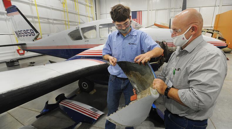Greene County Career Center student, Shiloh Arnold, left, works on a repairing a airplane cowling with his teacher, Jason Knisley, at the schools new hanger located at the Lewis A. Jackson Regional Airport in Xenia. MARSHALL GORBY\STAFF