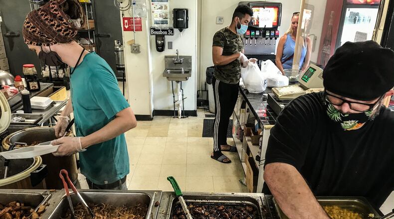 Bourbon Street Grill & Cafe employees (from left) Bobby Lauer, Aissa Ouland and Scott Freeman make food for walk-in customers Thursday at the restaurant on Brown Street in Dayton. Owner Hassan Abdalla said, “we never closed and never laid off anyone.” JIM NOELKER/STAFF