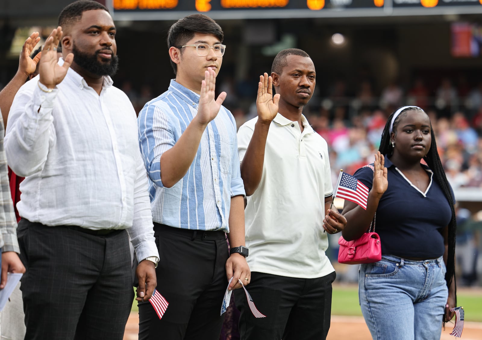 Twenty immigrants became U.S. citizens during a naturalization ceremony on Tuesday, Aug. 5, between the third and fourth innings of a Dayton Dragons game at Day Air Ballpark, including Tung Xuan Nghiem (center left), who immigrated from Vietnam. BRYANT BILLING / STAFF