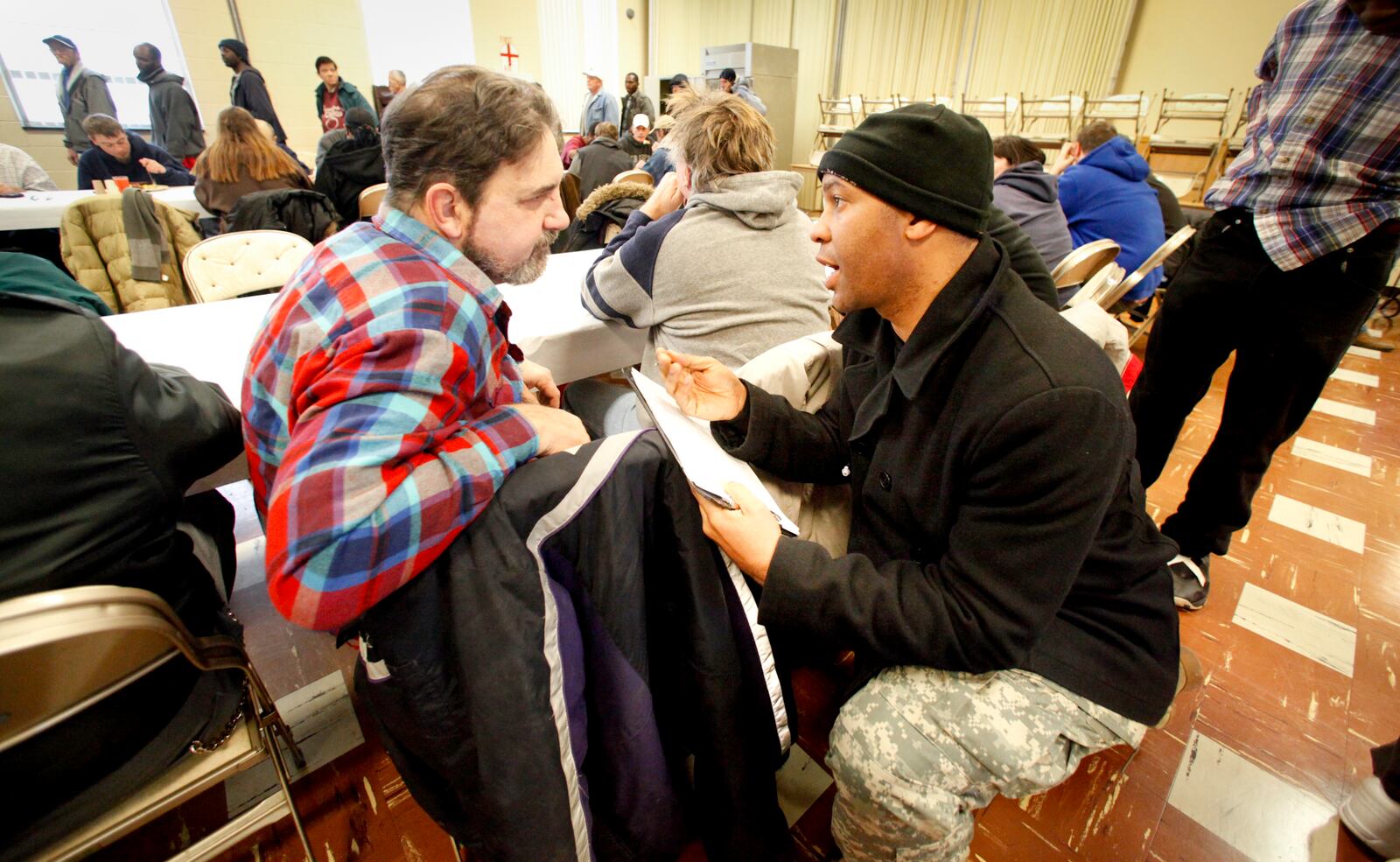 Army veteran Kevin Muhammad (right), the veteran outreach coordinator for Volunteers of America, who was himself once homeless, talks with homeless Dayton resident Greg Kendall while taking part in the Point in Time Count. Muhammad's volunteer team was counting those homeless Wednesday over the noon hour at Project Blessing, a free lunch program for the homeless and needy at St. Paul Evangelical Lutheran Church in Dayton. CHRIS STEWART / STAFF