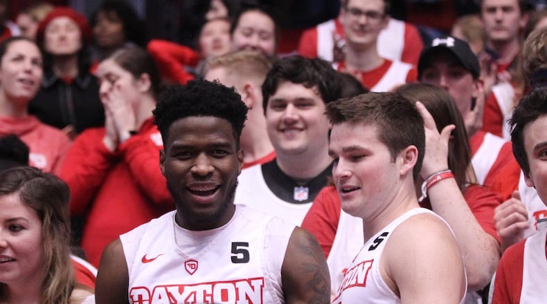 Dayton’s Jalen Crutcher and Joey Gruden celebrate with students after a victory against George Washington on Saturday, March 3, 2018, at UD Arena. David Jablonski/Staff